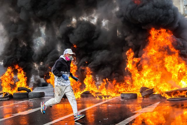 A fisherman runs past a barricade of tires and flames of fire during a demonstration in defense of fishing quotas in Valparaiso, Chile on March 11, 2025. Artisanal fishermen mobilized in Caleta Portales, Valparaíso Region, in defense of fishing quotas and to prevent the resumption of squid trawling. (Photo by Cristobal Basaure Araya/SOPA Images/Rex Features/Shutterstock)