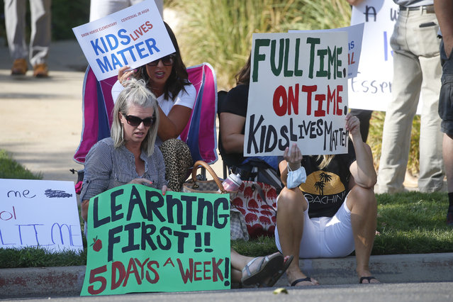 Staci Patrick, left, protests with others in front of the Davis School District Office, Tuesday, August 4, 2020, in Farmington, Utah. A group of parents protested the district's hybrid reopening plan because they would prefer their children to attend school five days a week. (Photo by Rick Bowmer/AP Photo)