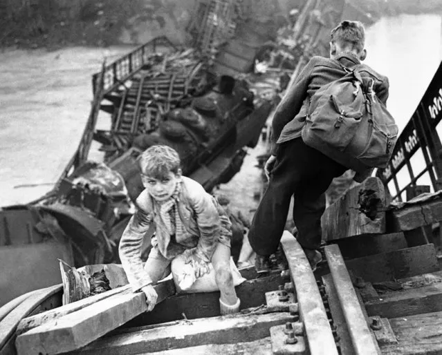 French children salvaging food from the cars of a wrecked train climb on a Moselle River railway bridge destroyed by the retreating Germans in France on December 5, 1944. (Photo by AP Photo)
