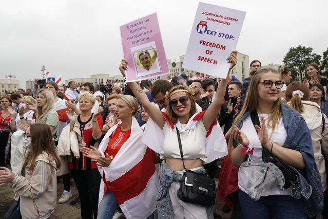 Belarusian opposition supporters, one of them holds posters, rally at Independence Square in Minsk, Belarus, Sunday, August 23, 2020. (Photo by Evgeniy Maloletka/AP Photo)