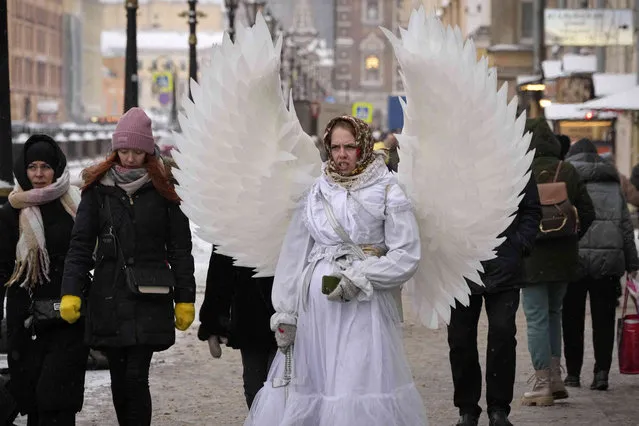 A street performer wearing an angel costume and earning money by posing for photos, walks in central St. Petersburg, Russia on Tuesday, December 6, 2022. (Photo by Dmitri Lovetsky/AP Photo)