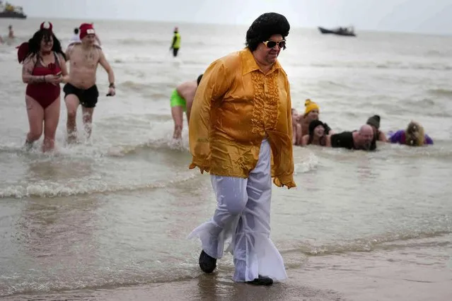 A man dressed in an Elvis costume gets out of the water after a swim in the North Sea as he celebrates the arrival of the New Year during the traditional New Year's Dive in Ostend, Belgium, Saturday, January 7, 2023. (Photo by Virginia Mayo/AP Photo)