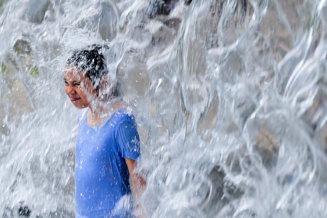 A child stands beneath the waterfall while taking a break from the heat in the Yards Park Canal Basin on July 17, 2025 in Washington, DC. The nation's capital is under a heat advisory with temperatures reaching the mid-90s and the heat index climbing over 100-degrees Fahrenheit. (Photo by USA Today)