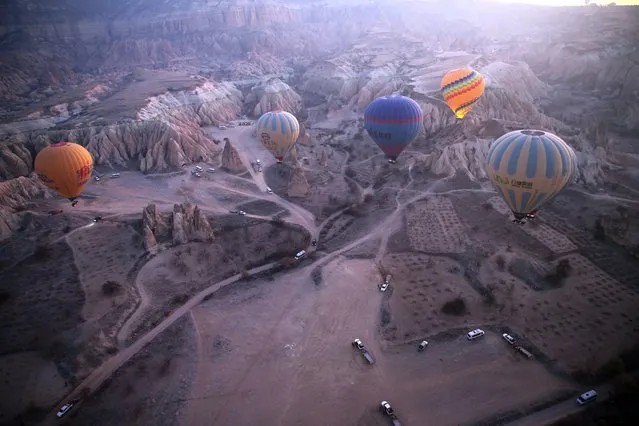 Hot air balloons glide over the historical Cappadocia region, located in Central Anatolia's Nevsehir province, Turkiye on January 1, 2023. In 2022, 662 thousand 443 tourists enjoyed the view of Cappadocia, a UNESCO World Heritage site, with hot air balloon tours. The region is famous for its chimney rocks, hot air balloon trips, underground cities and boutique hotels carved into rocks. (Photo by Behcet Alkan/Anadolu Agency via Getty Images)