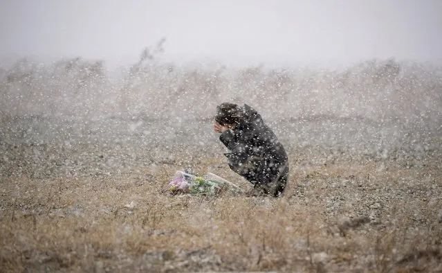 A woman prays for the deceased of the March 11, 2011 earthquake and tsunami, as snow falls, at a place where she was employed at a photo studio at the time, in Rikuzentakata, Iwate prefecture, in this file photo taken by Kyodo March 11, 2014. (Photo by Reuters/Kyodo News)