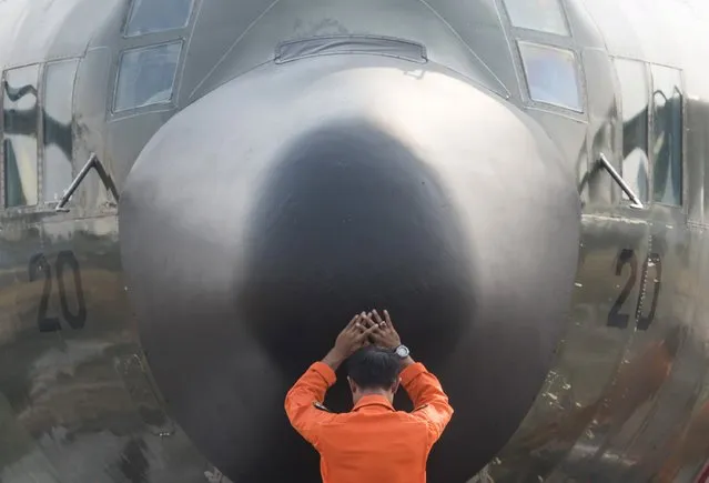 A crew member prays in front of a Hercules military aircraft before Indonesian soldiers are dispatched to exstinguish forest fires at Halim Perdanakusuma airport in Jakarta, in this October 27, 2015 photo taken by Antara Foto. (Photo by M. Agung Rajasa/Reuters/Antara Foto)
