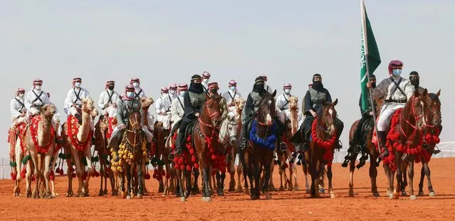 Saudi cameleers and horsewomen take part in a parade during the sixth edition of the King Abdulaziz Camel Festival in the Rumah region, some 161Km east of the capital Riyadh, on January 8, 2022. The festival introduced a round for women camel owners, allowing them for the first time to showcase their animals in a beauty contest. (Photo by Fayez Nureldine/AFP Photo)