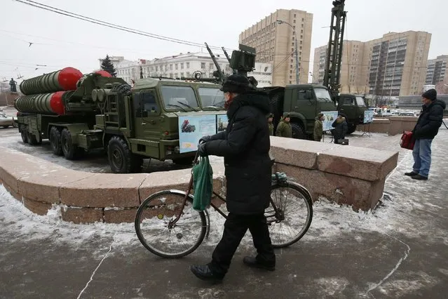 A man walks with his bicycle next to air-defence systems in front of Russian Army Theatre in Moscow, December 8, 2014. Air-defence systems are on display in central Moscow to celebrate the anniversary of the Russia's air defence forces, according to the spokesman of the Defense ministry. (Photo by Sergei Karpukhin/Reuters)