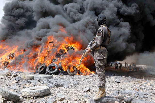 A soldier stands guard as illicit narcotics are being burned near Sanaa, Yemen, on July 1, 2025. Security forces of Yemen's Houthi group destroyed approximately 19 tons of narcotics, hashish and other illegal drugs here on Tuesday. (Photo by Xinhua News Agency/Rex Features/Shutterstock)