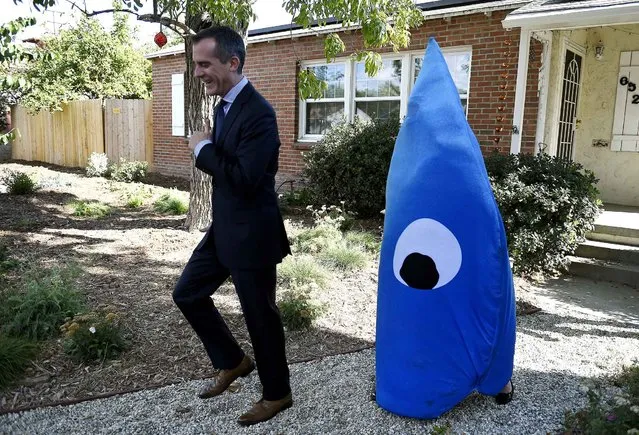 Los Angeles Mayor Eric Garcetti is followed by a person costumed as a drop of water as he arrives for a press conference to announce a pilot program to capture rainwater from residential rooftops and return it into the ground rather than into sewers, at a private home in Los Angeles, California on November 4, 2015. (Photo by Robyn Beck/AFP Photo)