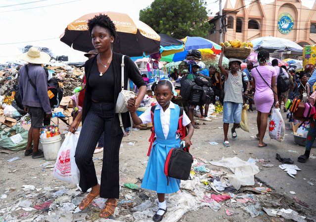 A woman walks a schoolgirl to class as the academic year begins after a U.N. vote to expand a security mission in a capital largely controlled by armed gangs and where conflict has displaced over a million people, in Port-au-Prince, Haiti, on October 1, 2025. (Photo by Egeder Pq Fildor/Reuters)