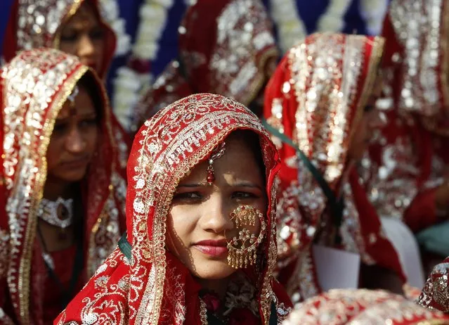 Muslim brides sit as they wait for their weddings to start during a mass marriage ceremony in the western Indian city of Ahmedabad December 25, 2014. A total of 80 Muslim couples from various parts of the city took wedding vows during the mass marriage ceremony organised by a Muslim voluntary organisation, organisers said. (Photo by Amit Dave/Reuters)