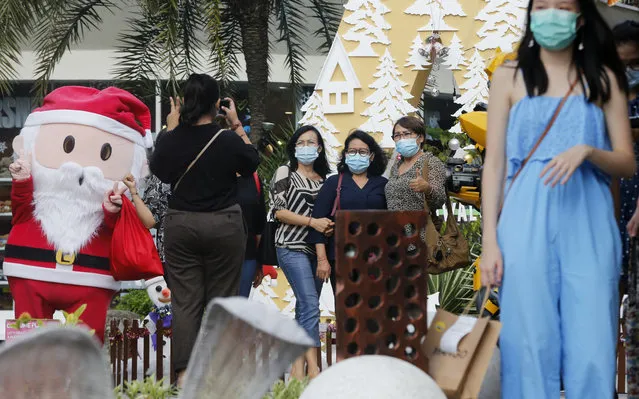 Women wearing masks to help curb the spread of the coronavirus pose for a photo with Santa in Bali, Indonesia on Tuesday, December 22, 2020. Indonesia has reported more than 600,000 cases of the coronavirus. (Photo by Firdia Lisnawati/AP Photo)