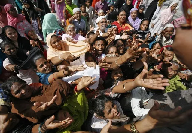 Muslim devotees raise their hands to receive sweets as offerings after prayers inside the shrine of Muslim saint Shah-e-Alam, during Urs in the western Indian city of Ahmedabad May 17, 2013. Urs is an annual festival held for over six days, commemorating the death anniversary of Sufi saint Khwaja Moinuddin Chishti at Ajmer in the desert Indian state of Rajasthan. The anniversary is celebrated in the seventh month of the Islamic lunar calendar. (Photo by Amit Dave/Reuters)