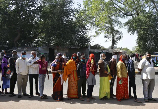 Indians wearing face masks as a precaution against the coronavirus line up outside a bank in Ahmedabad, India, Monday, December 28, 2020. India's confirmed coronavirus cases have crossed 10 million with new infections dipping to their lowest levels in three months, as the country prepares for a massive COVID-19 vaccination in the new year. (Photo by Ajit Solanki/AP Photo)