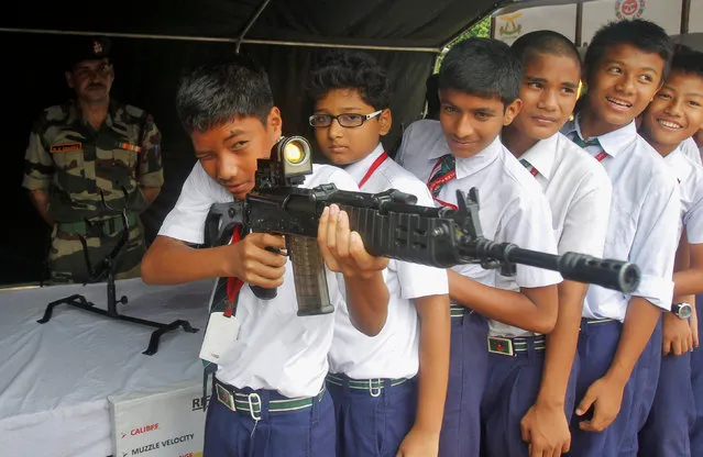 A school boy holds an INSAS (Indian Small Arms System) assault rifle on display during a programme organized by Assam Rifles, a paramilitary force, to attract youth in joining the force at their headquarters in Agartala, India, October 27, 2016. (Photo by Jayanta Dey/Reuters)