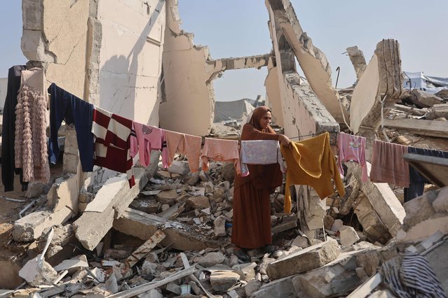 A Palestinian woman hangs clothes to dry amid the ruins of a building in Gaza City on November 18, 2025. Israel on November 18 hailed the US president's Gaza peace plan after its endorsement by the UN Security Council, as Hamas rejected the resolution which calls for the deployment of an international force in the Palestinian territory. (Photo by Omar Al-Qattaa/AFP Photo)