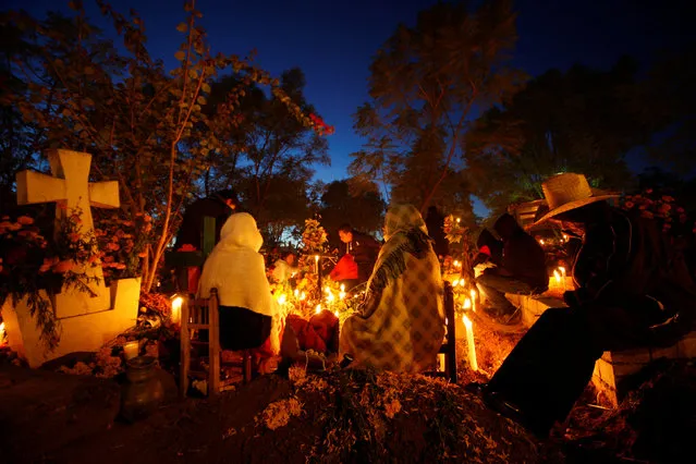 People sits next to graves on the Day of the Dead by paying homage to their dead relatives in Santa Maria Atzompa cemetery, Oaxaca, Mexico November 1, 2016. (Photo by Jorge Luis Plata/Reuters)