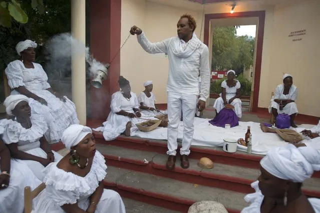 Voodoo Priest Herold Josue, also the National Director of Ethnology Bureau, swings incense as he leads a voodoo ceremony marking the fifth anniversary of the earthquake at the National Ethnology Bureau in Port-au-Prince, Haiti, Monday, January 12, 2015. (Photo by Dieu Nalio Chery/AP Photo)