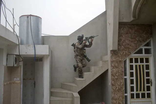 In this Tuesday, November 1, 2016 photo, an Iraqi special forces soldier climbs up the stairs of a house as his unit searches for an Islamic State militants sniper position in Gogjali, an eastern district of Mosul, Iraq. (Photo by Marko Drobnjakovic/AP Photo)