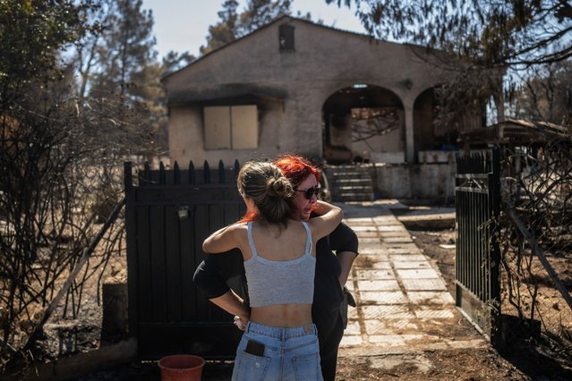 Relatives comfort each other after looking at the damage to their burnt home following a wildfire that hit the north-eastern suburbs of Athens, in Chalandri, suburb of Athens, on August 13, 2024. On August 13, 2024, Greece continued for the third consecutive day to fight a fire in the north-eastern suburbs of Athens, which has killed one person, forced thousands from their homes and polluted the air in the capital. (Photo by Angelos Tzortzinis/AFP Photo)
