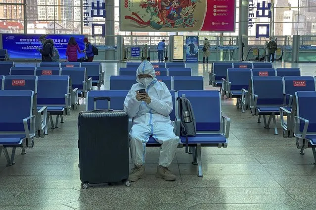 A traveller wearing protective gear to help curb the spread of the coronavirus sits alone on the bench as he waits for his train at the South Train Station in Beijing, Thursday, January 28, 2021. (Photo by Andy Wong/AP Photo)