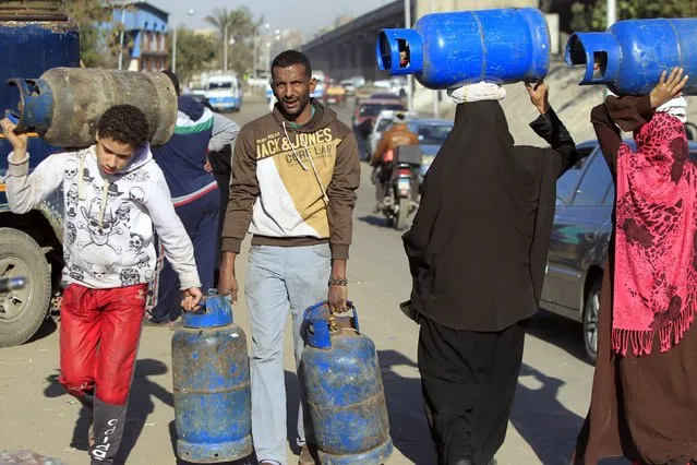 People carry gas cylinders to fill them in at a distribution point in Cairo January 19, 2015. (Photo by Mohamed Abd El Ghany/Reuters)