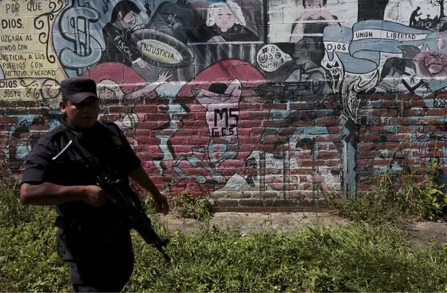 Policemen walk past graffiti associated with the Mara Salvatrucha gang in the Montreal neighborhood in Mejicanos, El Salvador December 9, 2015. The El Salvadorean police is conducting an operation to erase graffiti associated with gangs as part of a strategy to regain control in gang-controlled areas in this neighborhood, according to the police. (Photo by Jose Cabezas/Reuters)