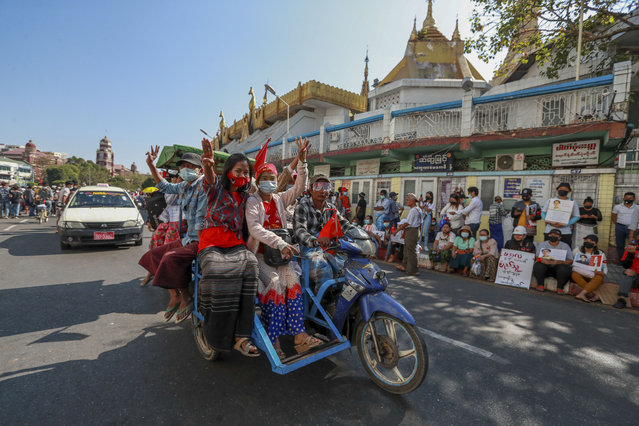 Demonstrator flash three-fingered salutes, a symbol of resistance, during a protest against the military coup in Yangon, Myanmar, Wednesday, February 10, 2021. (Photo by AP Photo/Stringer)
