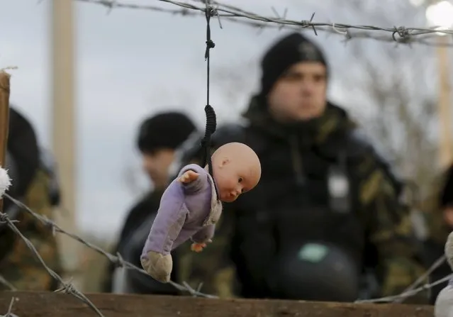 A doll, placed by stranded Iranian migrants, hangs from barbed wire in front of Macedonian police at the Greek-Macedonian border near to the Greek village of Idomeni November 29, 2015. (Photo by Yannis Behrakis/Reuters)