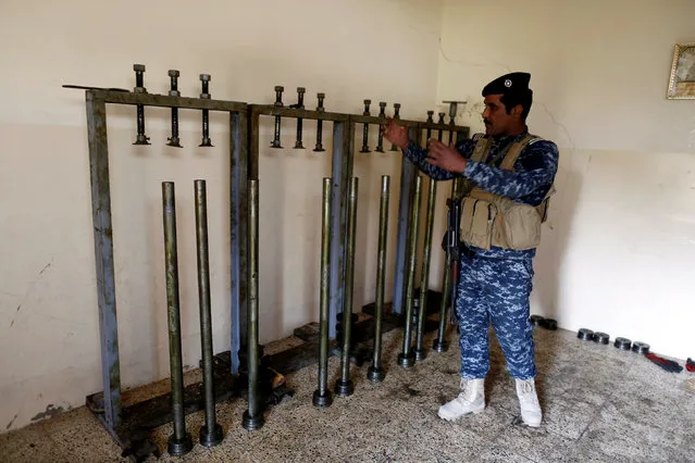 A federal policemen shows homemade rockets inside a house used as a homemade bomb factory by Islamic State militants in Samah district, eastern Mosul, Iraq November 12, 2016. (Photo by Zohra Bensemra/Reuters)