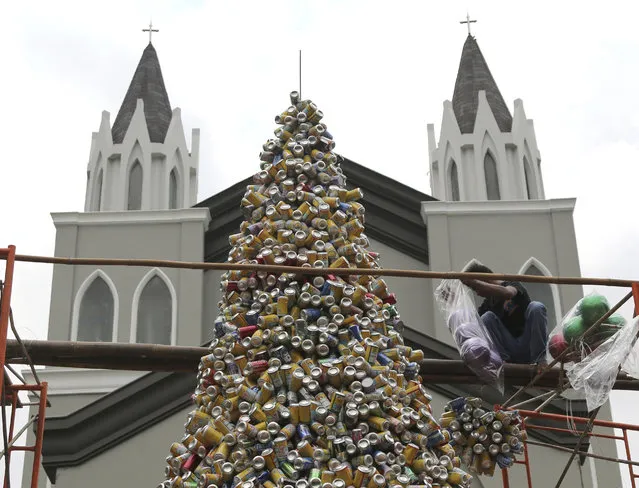 A worker arranges about 1,000 discarded beverage cans to form a Christmas tree in front of a church in Jakarta, Indonesia, Friday, December 18, 2015. (Photo by Tatan Syuflana/AP Photo)
