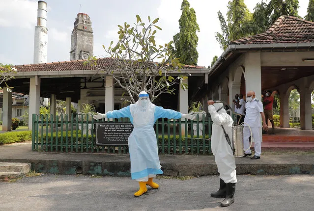 Sri Lankan health workers get disinfected after a cremation of COVID -19 victims at a cemetery in Colombo, Sri Lanka, Wednesday, February 10, 2021. (Photo by Eranga Jayawardena/AP Photo)