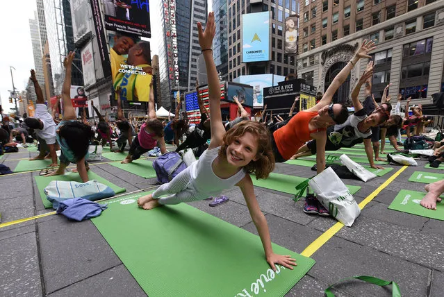 Kate Steinberg age 9 from Montreal, joins thousands of people as they participate in “Mind Over Madness Yoga”, an annual all-day outdoor yoga event during the summer solstice in Times Square on June 21, 2018 in New York. (Photo by Timothy A. Clary/AFP Photo)
