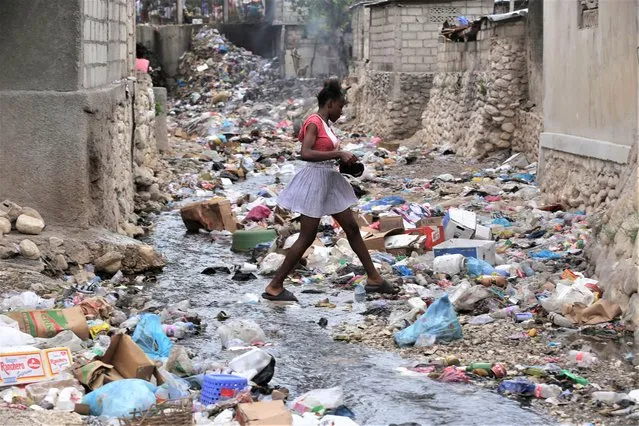 A girl walks through a ravine filled with garbage in Port-au-Prince, Haiti, Thursday, July 13, 2023. (Photo by Joseph Odelyn/AP Photo)