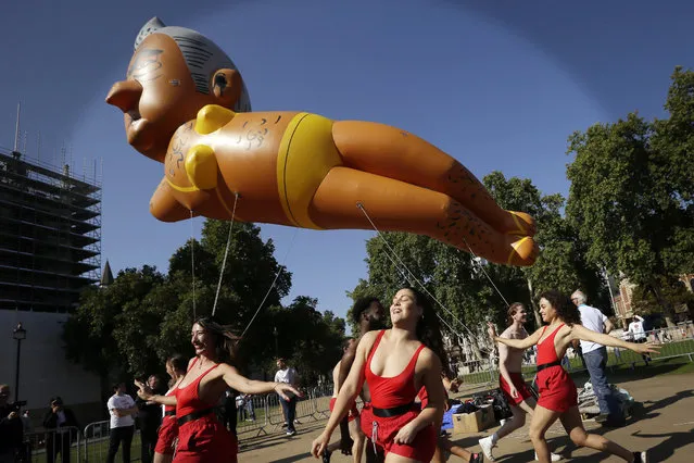 Dancers perform under an inflatable caricature balloon of Mayor of London, Sadiq Khan as it flies over Parliament Square in London, Saturday, September 1, 2018. Organizer Yanny Bruere raised more than 58,000 pounds ($75,000) through the Crowdfunder website for the 29-foot (8.8-meter) blimp as part of a campaign to oust Khan from his post. Khan angered some people in the British capital and elsewhere last month when he allowed a balloon caricaturing Donald Trump as an angry baby to float above the city while the U.S. president was in England. (Photo by Tim Ireland/AP Photo)