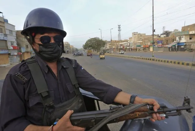 A police officer take position on a vehicle at a deserted road due to strikes called by the the country's religious political parties over the security forces's crackdown against a banned Tehreek-e-Labaik Pakistan party, in Karachi, Pakistan, Monday, April 19, 2021. An outlawed Pakistani Islamist political group freed 11 policemen almost a day after taking them hostage in the eastern city of Lahore amid violent clashes with security forces, the country's interior minister said Monday. (Photo by Fareed Khan/AP Photo)