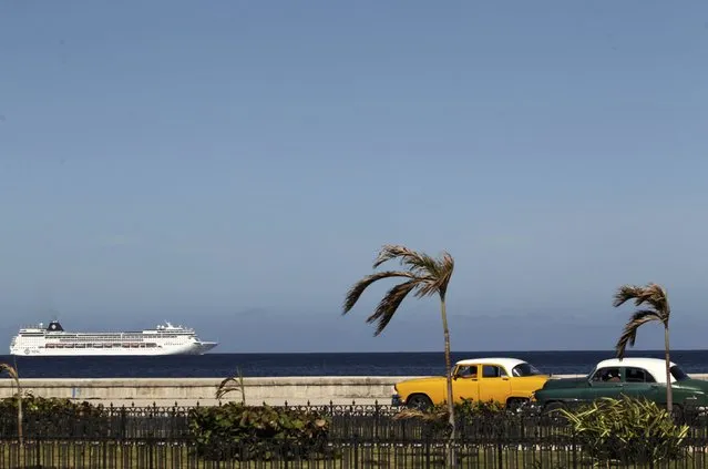A cruise ship sails offshore as a pair of vintage American cars pass by while the country pays tribute to Cuba's late President Fidel Castro in Havana, Cuba, November 29, 2016. (Photo by Reuters/Stringer)