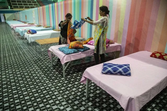 Workers arrange beds at a COVID-19 treatment facility newly set up at an indoor stadium in Gauhati, India, Monday, April 19, 2021. (Photo by Anupam Nath/AP Photo)