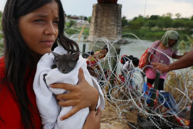 A migrant from Venezuela holds her cat named "Grey" that she picked up along the route, after crossing the Rio Grande and making her way through the razor wire into the United States in Eagle Pass, Texas, U.S., September 26, 2023. (Photo by Brian Snyder/Reuters)