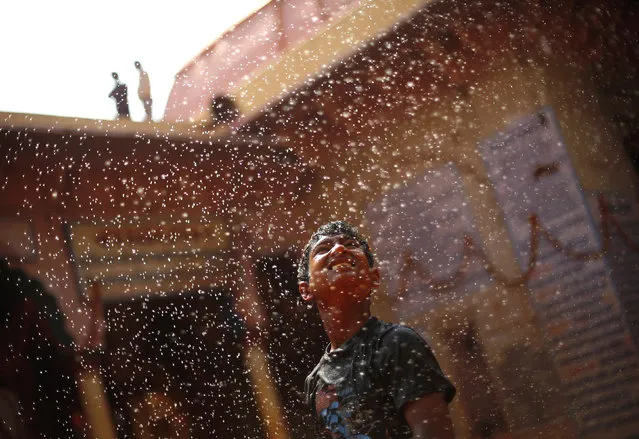 A boy stands under a shower during “Huranga” at Dauji temple, near the northern Indian city of Mathura, March 7, 2015. (Photo by Adnan Abidi/Reuters)