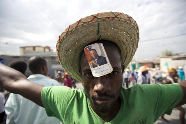 A demonstrator with a picture of former president Jean Bertrand Aristide on his forehead takes part in a protest after it was announced that the runoff January 24, presidential election had been postponed, in Port-au-Prince, Haiti, Friday, Jan. 22, 2016. The Provisional Electoral Council in Haiti has postponed the election amid escalating protests by the opposition, which claims the first round was marred by fraud in favor of a government-backed candidate. (Photo by Dieu Nalio Chery/AP Photo)