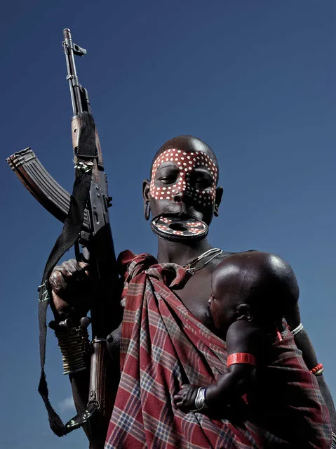 A tribeswoman holds a gun and a baby, taken in South Omo, Ethiopia, undated. As the newest smartphones and technology are released in our fast-paced society, there are civilizations deep in Africa untouched by outside influences. Approximately 24 indigenous tribes live in South Omo, Ethiopia, whom still retain their cultural traditions and attire. However as more Western tourists begin to visit the land lost in time, the modern world is consequently being introduced into the tribe's culture. (Photo by Neil Thomas/Barcroft Images)