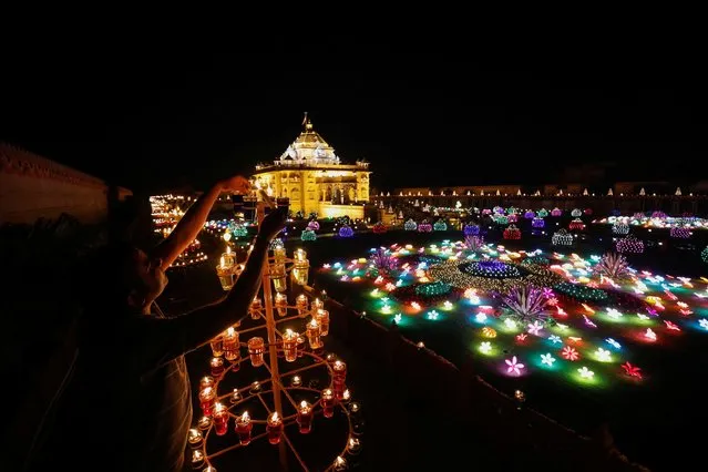 A devotee lights lamps at the Akshardham temple during celebrations on the eve of Diwali, the Hindu festival of lights, in Gandhinagar, India on November 11, 2023. (Photo by Amit Dave/Reuters)