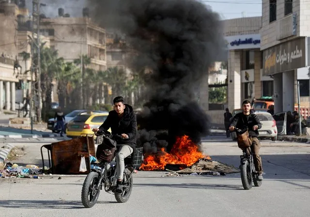Palestinian men ride bikes past a burning fire during an Israeli raid in the Balata refugee camp in Nablus, amid the ongoing conflict between Israel and the Palestinian Islamist group Hamas, in the Israeli-occupied West Bank on November 23, 2023. (Photo by Raneen Sawafta/Reuters)