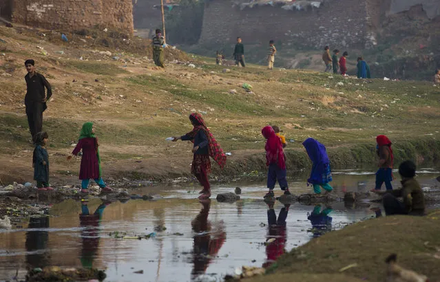 Displaced children from a Pakistani tribal area of Bajur due to fighting between militants and security forces cross a stream in Islamabad's slum, Pakistan, Wednesday, December 18, 2013. Thousands of locally displaced people and refugees from neighboring Afghanistan live in Islamabad's suburbs without basic amenities. (Photo by B. K. Bangash/AP Photo)