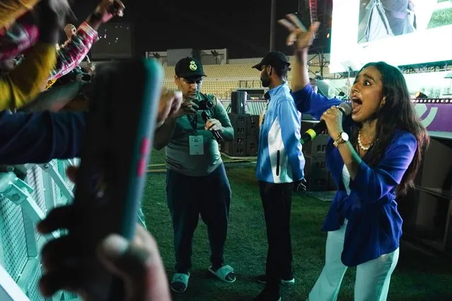 MC Lincia Rosario dances in front of laborers at a fan festival at the Asian Town cricket stadium in Doha, Qatar, Friday, November 25, 2022. Far from the luxury hotels and sprawling new stadiums emblematic of Doha during the World Cup, scores of soccer-mad South Asian workers poured into a converted cricket stadium in the city's desert outskirts to enjoy the tournament they helped create. (Photo by Jon Gambrell/AP Photo)