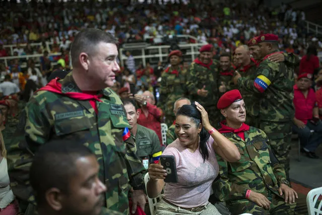 In this February 6, 2019 photo, the wife of a soldier who was part of the group that attacked the presidential palace in a failed 1992 military coup organized by the late Hugo Chavez, checks her hair minutes before the start of the weekly, live TV program coined: “Con el Mazo Dando”, or “Hitting it With a Sledgehammer”, inside an aviation academy in Maracay, Venezuela. For government supporters attending the program, the enthusiasm for the show's host Diosdado Cabello, who the U.S. and European Union have sanctioned for human rights abuses and corruption, bordered on Elvis Presley-like idolatry. (Photo by Rodrigo Abd/AP Photo)