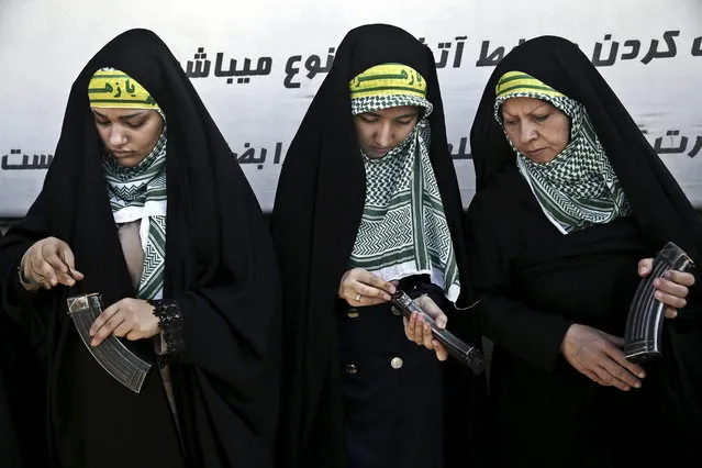 In this Thursday, August 22, 2013 photo, female members of the Basij paramilitary militia load their rifles during a training session in Tehran, Iran. With a presence in nearly every city and town across Iran, the paramilitary Basij volunteer corps has an ever-increasing influence on life in the Islamic Republic. (Photo by Ebrahim Noroozi/AP Photo)