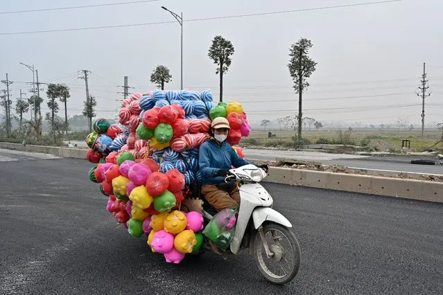 A woman rides a motorbike carrying plastic toys on the outskirts of Hanoi on January 5, 2024. (Photo by Nhac Nguyen/AFP Photo)